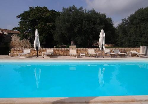 a large swimming pool with chairs and umbrellas at Il Carosello dei Baroni in Noto