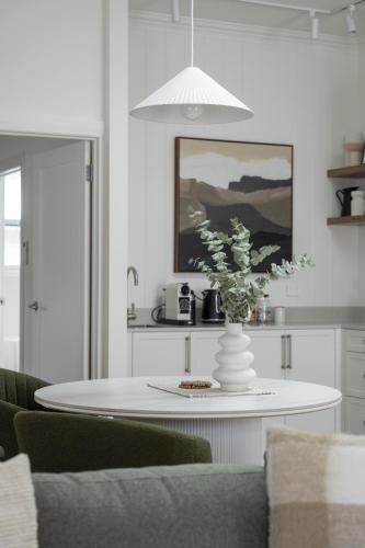 a white table with a vase of flowers on it at Field Street Cottages 'Studio' - Centrally Located Luxury in McLaren Vale