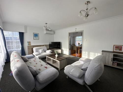 a living room with a couch and chairs and a table at Gracious 3 Bdrm House in Chartwell in Hamilton