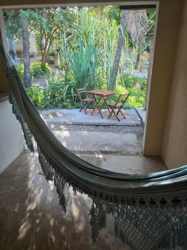 a hammock with a table and a bench in a courtyard at Stay Cool Pipa in Pipa