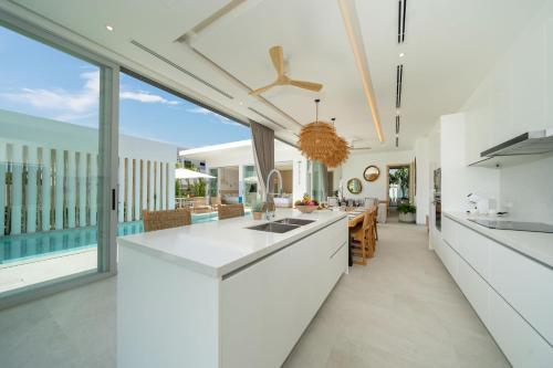 a kitchen with white countertops and a large window at Tropical Brand New 4BR Pool Villa Mina, just 5 min Drive from Naiharn in Rawai Beach