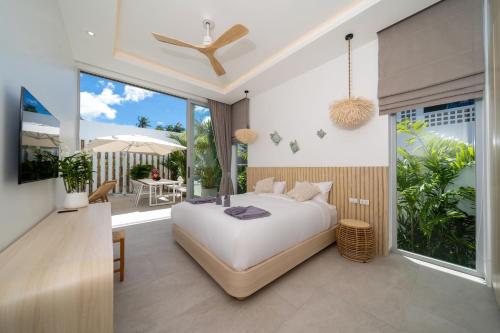 ラワイビーチにあるTropical Brand New 4BR Pool Villa Mina, just 5 min Drive from Naiharnの大きなベッドとバルコニーのある寝室