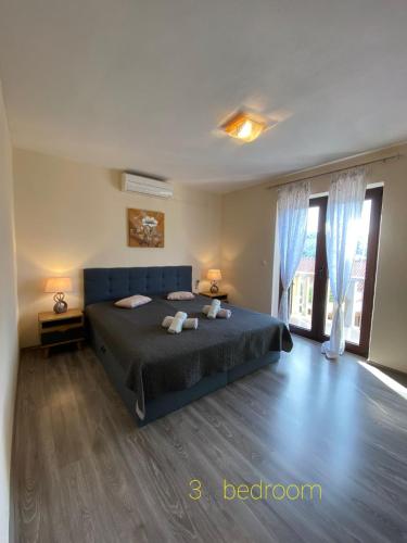 a bedroom with a blue bed and a large window at Apartments " Happy villa " in Splitska