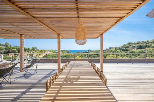 une terrasse en bois avec vue sur l'océan dans l'établissement Superbe Villa Porto Vecchio vue mer plage à pied, à Porto-Vecchio