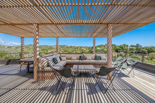 une terrasse avec une pergola, une table et des chaises dans l'établissement Superbe Villa Porto Vecchio vue mer plage à pied, à Porto-Vecchio
