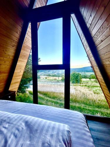 a bed in a room with a large window at Nemes Chalet A Frame in Văleni