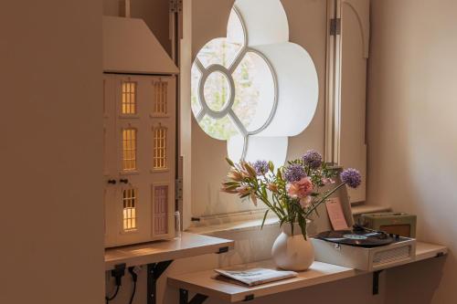 a vase of flowers on a table next to a window at No 15 by GuestHouse, Bath in Bath