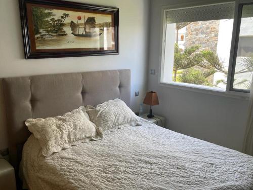 a bedroom with a white bed with a window at Résidence Perla Saidia-seulement pour les familles- Plage à 5 min à pieds - Piscine en travaux in Saidia 