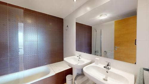 a bathroom with two sinks and a tub and a mirror at Mar Menor Golf Resort in Murcia