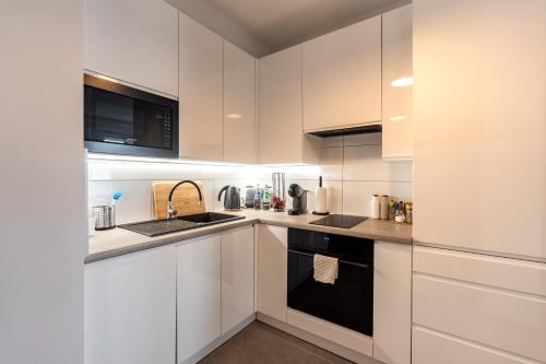 a kitchen with white cabinets and black appliances at Apartementy Plac Solny 20 in Wrocław