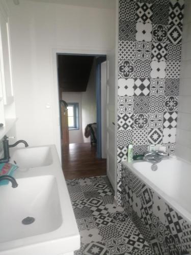 La salle de bains est pourvue de deux lavabos et d'un mur en carrelage. dans l'établissement Grande maison dans un village côtier du Finistère, à Guissény