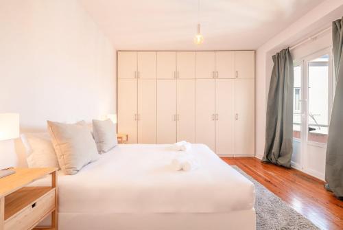 une chambre avec un grand lit blanc et un bureau dans l'établissement GuestReady - City views and comfort in Arroios, à Lisbonne