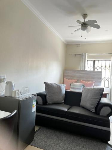 a black couch in a living room with a ceiling fan at Montrose BnB in Margate
