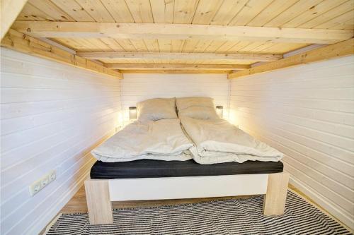 a bed in a small room with a wooden ceiling at Tiny House Strandhäkster in Westerdeichstrich