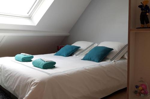 - un lit blanc avec des oreillers bleus dans l'établissement Duplex Le Colombier - Beautiful Charming Home, à Magny-le-Hongre