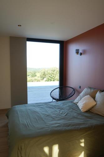 une chambre avec un lit avec une grande fenêtre dans l'établissement Maison d'architecte vue panoramique piscine miroir, à Montclus