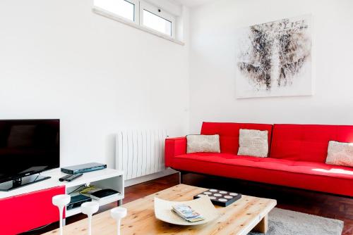 a living room with a red couch and a coffee table at Park View Central Apartment in Cascais in Cascais