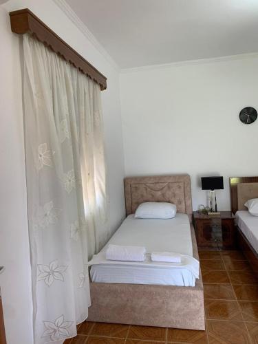 a bedroom with a bed and a window with curtains at Rama Guest House in Berat