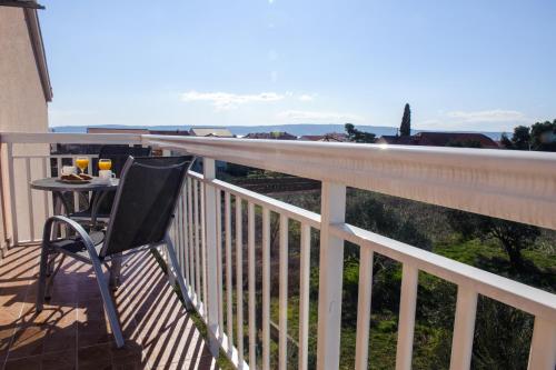 a black chair sitting on a balcony with a table at Apartman Sunny Vacay in Kaštela