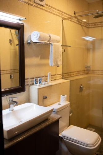 a bathroom with a sink and a toilet and a mirror at The Monarch Hotel in Nairobi