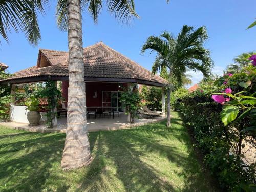 a house with palm trees in front of a yard at Agence Adjana Resort - Résidence du Port 3 in Sali Tapé