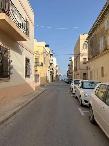 a street with cars parked on the side of a building at Lucija's Guesthouse in Birżebbuġa