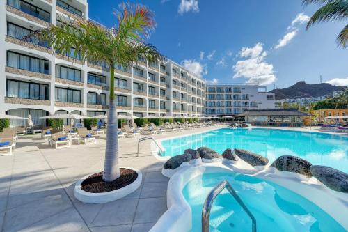 a large swimming pool with a hotel in the background at H10 Costa Mogán - Adults Only in Playa del Cura