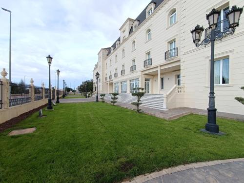a large white building with a green lawn in front of it at Hotel Bossh Alicia in Albacete