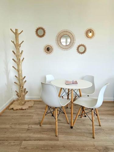 - une salle à manger avec une table, des chaises et des miroirs dans l'établissement Logement 68 m2 confortable et cosy - Corrèze, à Saint-Privat