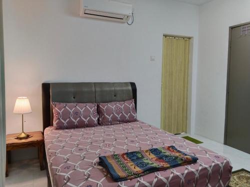 a bedroom with a large bed with a purple comforter at Kayu Cengal Homestay in Seri Iskandar