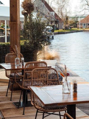 a patio with tables and chairs next to a river at Schippershuis Terherne in Terherne