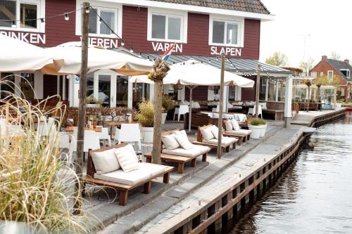 a restaurant with chairs and umbrellas next to a river at Schippershuis Terherne in Terherne