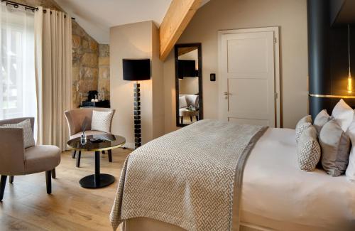 a bedroom with a bed and a table and chairs at Domaine de la Klauss & Spa, Restaurant Gastronomique Le K in Montenach