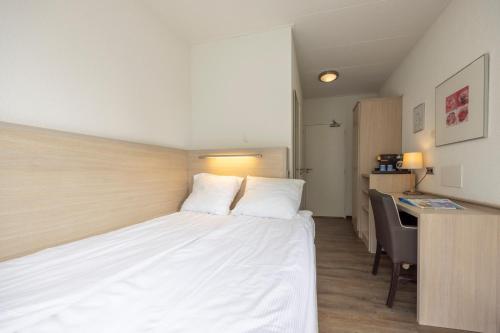 a bedroom with a white bed with a desk and a computer at Fletcher Hotel Restaurant De Witte Raaf in Noordwijk