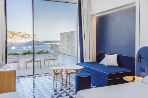 a hotel room with a blue couch and a balcony at Hotel La Roccia in Castro di Lecce