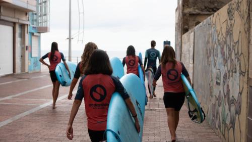 a group of people walking down a sidewalk with surfboards at Tamaran House in Las Palmas de Gran Canaria