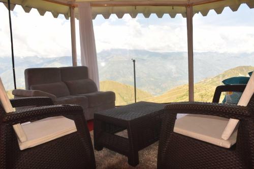 a living room with a table and chairs and a view of mountains at Glamping del Occidente in Cativo