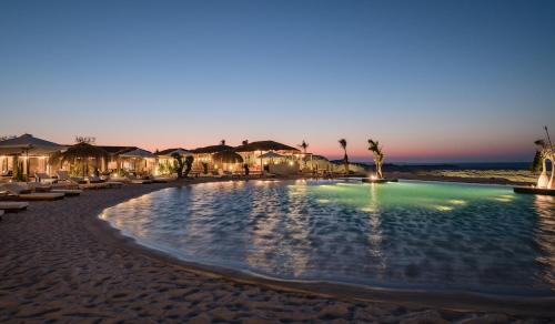 a swimming pool on the beach at sunset at Marmarica Boutique Cabanas - Ras El Hekma - North Coast Top Rated Luxury Stay in Marsa Matruh