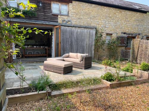 a couch sitting on a patio in front of a house at The Carriage House, Haversham near Milton Keynes in Haversham