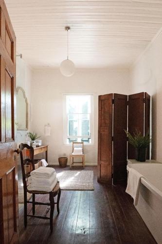 a living room with a table and a bed and a window at Langhuis Guesthouse in Graaff-Reinet