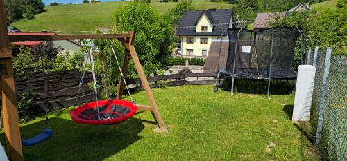 a playground with a red swing in a yard at Domek Nad Czorsztynem in Mizerna