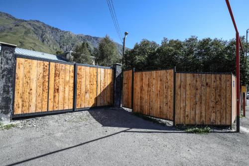 a wooden fence with a gate in a driveway at Cottages DILA in Stepantsminda