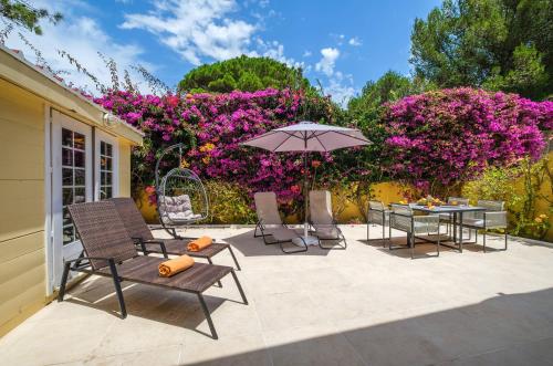 a patio with chairs and an umbrella and flowers at Seafront Unit 1 in Cascais