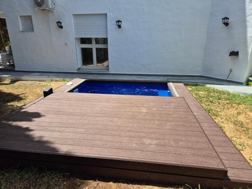 a pool with a wooden deck in front of a house at Maison moderne avec Piscine et accès plage - Résidence Jinen Hammamet in Hammamet Sud