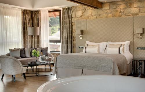 a bedroom with a bed and a couch and a tub at Domaine de la Klauss & Spa, Restaurant Gastronomique Le K in Montenach