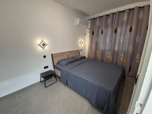 a bedroom with a bed and a gray curtain at Maison moderne avec Piscine et accès plage - Résidence Jinen Hammamet in Hammamet Sud