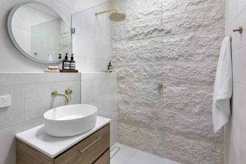 a white bathroom with a sink and a mirror at Luxury Manly Oceanfront Getaway in Sydney