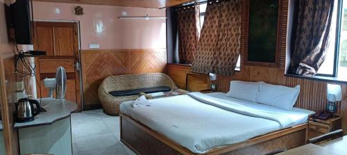 a bedroom with a bed and a chair in it at Hotel Assembly in Shillong