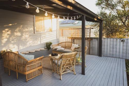 a deck with chairs and a table and a couch at Halcyon Days your perfect getaway Sunday late check out, pet friendly! in Cessnock