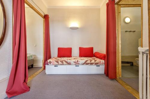 a bedroom with a bed with red curtains and a mirror at Gîte de groupe Val dOrey in Ruffieu